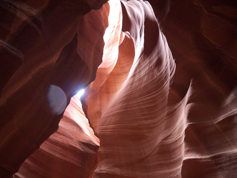 Looking up at Low Antelope canyon, stunning view, eroded red sandstone walls, sun light falling on dark red canyon walls