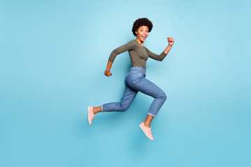 Fototapeta na wymiar Full length body size photo of cheerful fast quick black woman jumping running towards shopping mall as rapidly as possible wearing jeans denim isolated over vivid blue color background