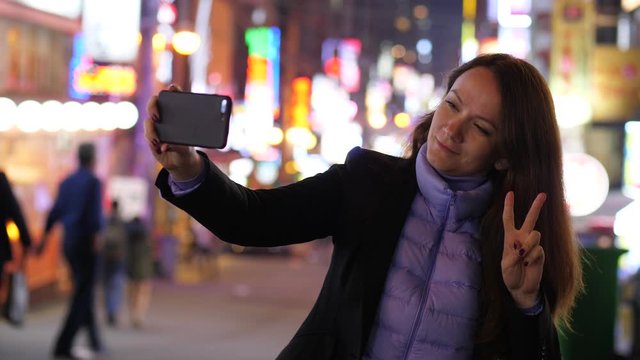 Tourist woman take selfie photo at night time, restaurants street at Seoul. Lady using smartphone to make pictures of herself, blurred background, popular dinning area at Yeoksam dong, Gangnam