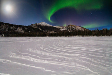 Snow-capped mountains at night under the northern lights. Canada.
