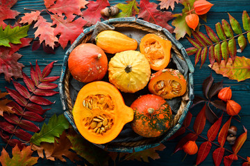 Autumn vegetables. Colored pumpkins with autumn leaves. flat lay. On a blue wooden background. Top view. Free space for your text.