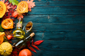 Pumpkin oil and pumpkins. Autumn vegetables. flat lay. On a blue wooden background. Top view. Free space for your text.