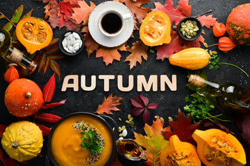 Autumn background with coffee, pumpkin, autumn leaves and seeds. flat lay. On a black stone background. Top view. Free space for your text.