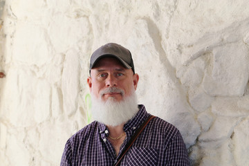 Bearded man against white stone wall