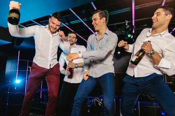 Group of smiling male friends having fun in night club