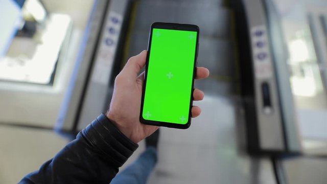 POV, male hand using smartphone with green screen chroma key in the escalator of shopping mall