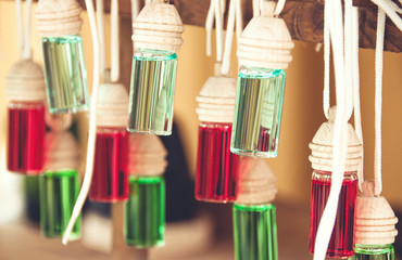 Variety of car air fresheners. Little glass bottles with wooden lids and colored aromatic liquid.