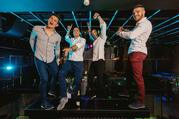 Group of smiling male friends having fun in night club