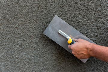 Application of decorative plaster on wall using construction tool.