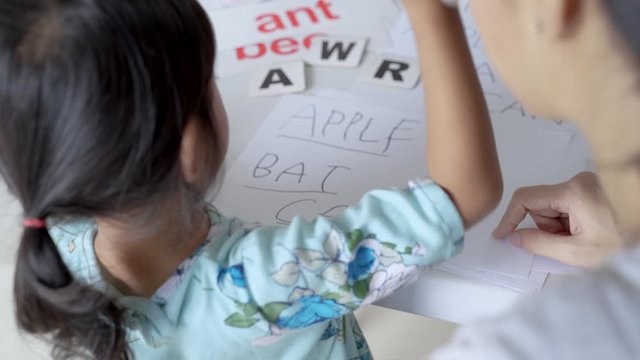 happy mother teaching her daughter the basic to read and write at home. toddler kindergarten student