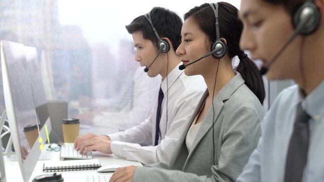 Smiling friendly woman working as telemarketing customer service agents with male team in office