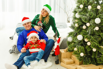 The charming family sitting near Christmas Tree