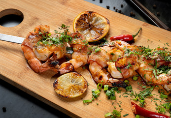 Shrimp shrimp, decorated with herbs, next to the grilled lemons.