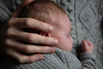 Fototapeta premium A father holding his baby son on his chest. Family bonding. Fatherhood