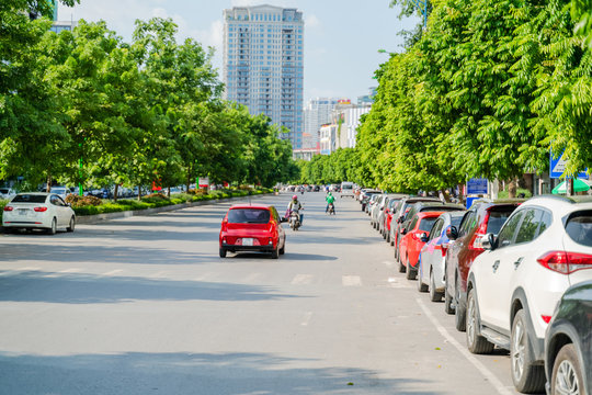 Cars parked on the urban street side, with green tree line. Green city concept