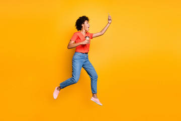 Fototapeta na wymiar Full body profile side photo of crazy funny wavy hair beautiful girl use cellphone take selfie trip journey hold mug jump wear t-shirt jeans sneakers isolated over yellow color background