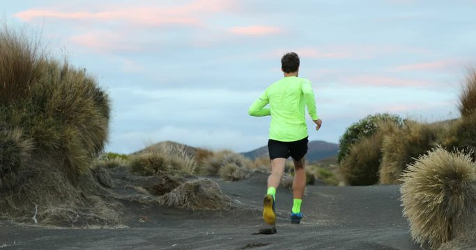 Trail runner man running in New Zealand mountains nature. Sport athlete at dusk landscape background near tongariro national park. Active health and motivation lifestyle. 59.94 FPS slow motion.