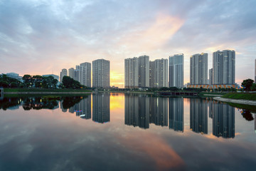 Fototapeta na wymiar Buildings with reflections on lake at sunset at Thanh Xuan park. Hanoi cityscape at twilight period