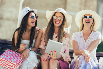 Three girls with colorful shopping bags using digital tablet and credit card