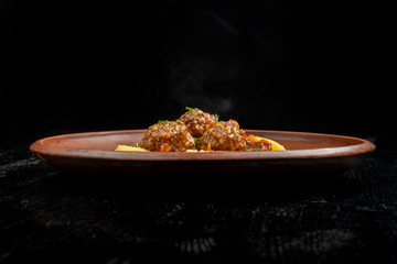 Meatballs with potato wedges on a beautiful clay plate.