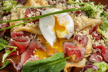 Diet menu. Salad with chopped steak, poached eggs, pancakes, green salad. Sprinkled with grated cheese.