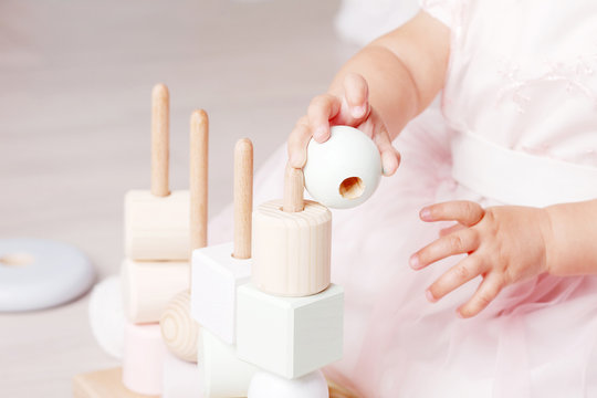 Child girl playing with a wooden toy sorter. Little cute girl with  natural toys.  Close up picture