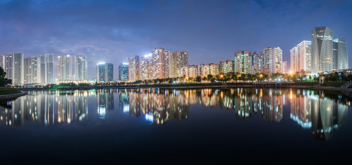Fototapeta premium Buildings with reflections on lake at twilight at Thanh Xuan park. Hanoi cityscape at twilight period