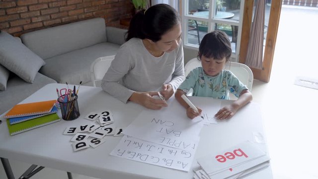 mother and daughter learning to read and write letter at home together. homeschooling activity