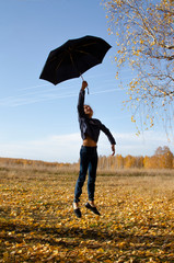 flying girl with umbrella in the autumn forest with falling leaves