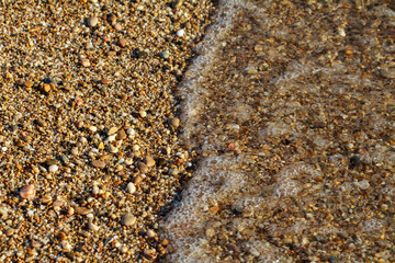 sea pebbles colored granite on the beach background stones. The shore of the beach with sand and pebbles washed by the waves of the sea.