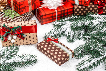 Christmas gifts with with Christmas tree branches and snow on wooden background closeup