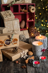 Christmas arrangement with presents, wrapped gifts, candles, festive decorations and Christmas tree brunch with light on background, vertical composition
