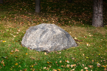Big stone on the lawn. Landscaping in an urban environment. Stone in the park. Rock garden.