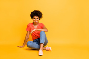 Portrait of positive charming cheerful girl sit have free time enjoy rest relax weekends wear casual style clothes sneakers isolated over yellow bright color background