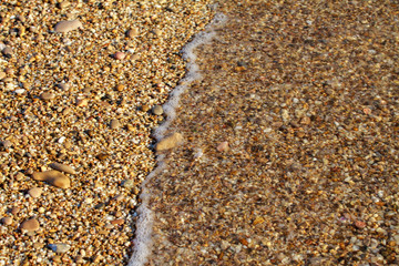 sea pebbles colored granite on the beach background stones. The shore of the beach with sand and pebbles washed by the waves of the sea.