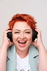 excited redhead woman listening music in headphones