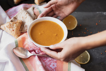 Hands grabbing a bowl of soup