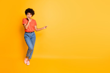 Full length body size copyspace photo of shocked stylish trendy pretty sweet cute lovely black woman wearing jeans denim t-shirt pointing at emptiness isolated over yellow vivid color background