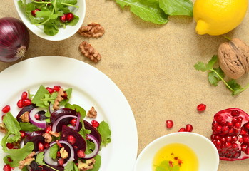 Beetroot salad with arugula, walnuts and pomegranate seeds, top view, copy space