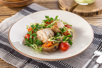 baked chicken served with roasted potato wedges and greens on white plate on wooden table