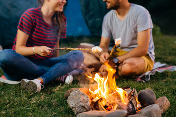 closeup of friends barbecuing marshmallows on camping fire