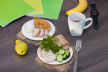 Protein breakfast with chiken roll, bread, egg before school, work, university on the wooden background with books.