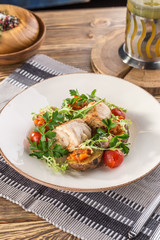 baked chicken served with roasted potato wedges and greens on white plate on wooden table