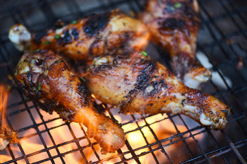 Grilled chicken legs barbecue with herbs and spices - Tasty chicken legs on the grill with fire flames marinated with ingredients cooking picnic outdoors