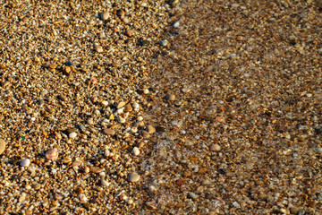 sea pebbles colored granite on the beach background stones. The shore of the beach with sand and pebbles washed by the waves of the sea.