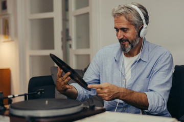 mid aged man playing records at his home 