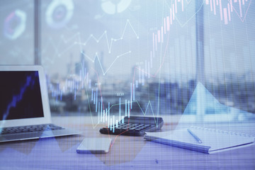 Stock market graph on background with desk and personal computer. Double exposure. Concept of financial analysis.
