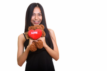 Young happy Asian teenage girl smiling while holding teddy bear