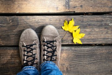 Conceptual image of legs in boots and autumn leaves.