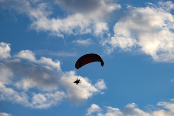 Paraglider silhouette over blue sky.